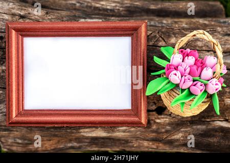 Cornice con carta bianca e cestino di tulipani freschi sul tavolo Foto Stock