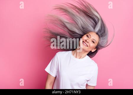 Ritratto di anziano donna sorridente felice gettando lunghi capelli grigi isolato pastello rosa sfondo colore Foto Stock