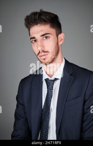 Ritratto di giovane uomo con abito blu scuro e cravatta blu scuro con puntini rosso e blu chiaro. Foto Stock
