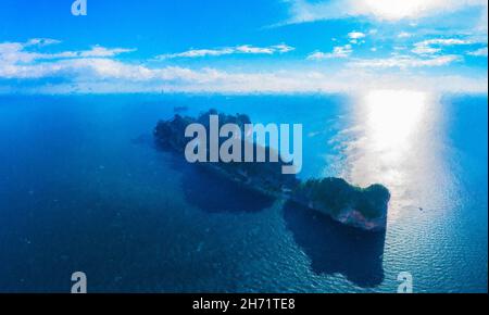 Pittura Vista dall'alto dell'isola tropicale con rocce calcaree, spiaggia bianca e acqua limpida blu. Vista aerea della baia Maya con molte barche e motoscafi ab Foto Stock