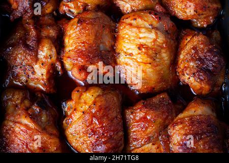 Cosce di pollo arrosto sfondo. Le parti di pollo al forno si trovano su una superficie piana e riempiono l'intera cornice dell'immagine. Primo piano. Vista dall'alto Foto Stock