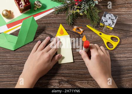 Passo di istruzioni 10. Biglietto d'auguri natalizio regalo candela origami su tavolo in legno. Progetto d'arte per bambini, fatto a mano, artigianato per bambini. Foto Stock