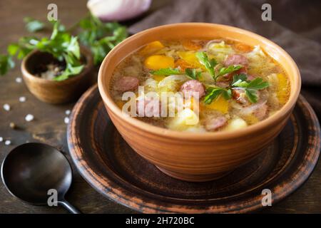 Cucina ceca: Zuppa di cavolo Zelnacka tradizionale con salsicce e verdure in una ciotola su un rustico tavolo di legno. Foto Stock