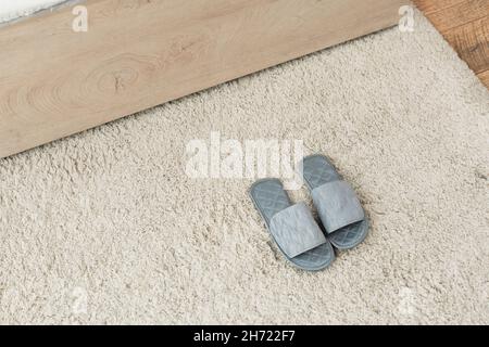vista ad angolo alto delle pantofole grigie su tappeto beige Foto Stock