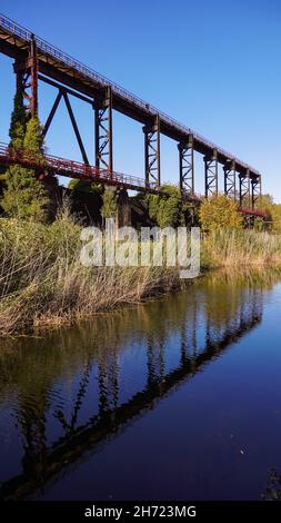Vecchi ponti industriali arrugginiti in contrasto con la natura Foto Stock