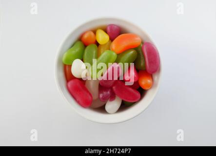 Piccola pentola di fagioli gelatinei colorati assortiti su sfondo bianco con spazio per la copia Foto Stock