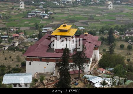 Il Paro Rinchen Pung Dzong e campi di riso nella valle sottostante, come visto dalla Ta Dzong o torre di guardia. Paro, Bhutan. Foto Stock