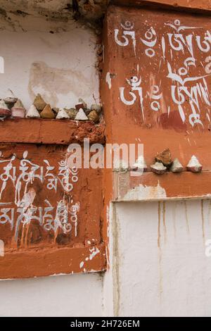 Sceneggiatura tibetana e tsatas su un muro al monastero di Dechen Phodrang a Thimphu, Bhutan. Foto Stock