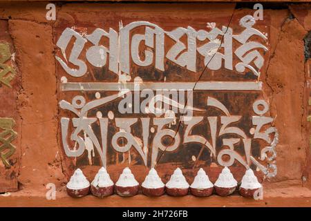 Sceneggiatura tibetana e tsatas su un muro al monastero di Dechen Phodrang a Thimphu, Bhutan. Foto Stock