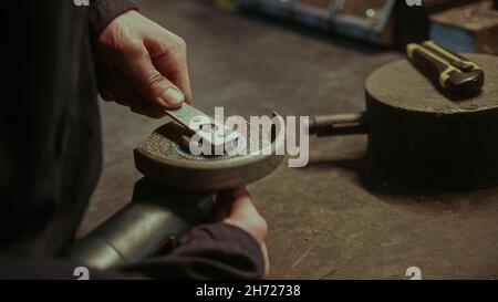 Primo piano del personale del fabbro che cambia testa della macinatrice del ferro Foto Stock