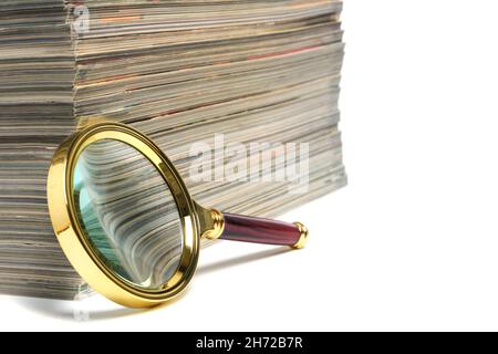 Pila di riviste e lente d'ingrandimento su sfondo bianco.concetto di apprendimento e ricerca della conoscenza Foto Stock