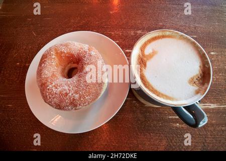 Ciambella italiana e cappuccino caffè su un tavolo da caffe' esterno Liverpool merseyside uk Foto Stock