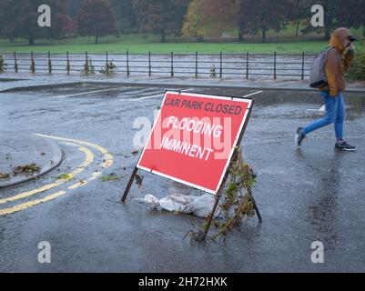 Segnale di inondazione imminente presso le Whitesands nel centro di Dumfries, Scozia, 29 ottobre 2021. Un passante cerca di proteggersi dalla pioggia. Foto Stock