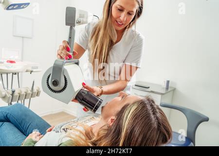 Un dentista attraente che assume una radiografia della bocca di un paziente. Concetto di cura dentale, assistenza sanitaria. Foto Stock