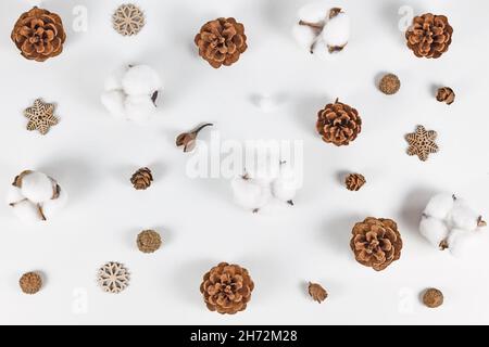 Sistemazione invernale con coni di abete, ornamenti in fiocco di neve e Gossypium di cotone su sfondo bianco Foto Stock