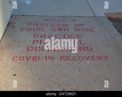 Fare pratica fisica distancing messaggio stenciled su un marciapiede vicino al marciapiede a Ocean City, Maryland, USA, 2021, © Katharine Andriotis Foto Stock