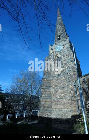 Vetrate colorate e chiesa del Santo Sepolcro Northampton UK torre in pietra edificio con orologio e finestre blu cielo cielo blu orologio e sagrato Foto Stock