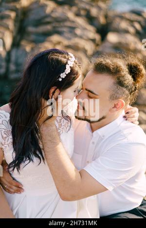 Lo sposo abbraccia la sposa seduta tra le braccia Foto Stock