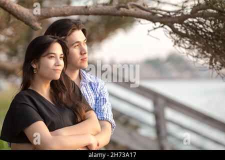 Goodlooking giovane biraciale asiatico caucasico misto coppia di corsa godendo insieme tempo dal lago al tramonto nel nord-ovest del Pacifico Foto Stock