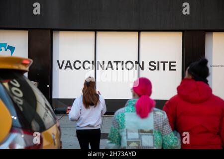 New York, Stati Uniti. 19 Nov 2021. I pedoni camminano di fronte a un sito di vaccinazione COVID-19 nel quartiere di Brooklyn di New York, Stati Uniti, 19 novembre 2021. La Food and Drug Administration (FDA) statunitense il venerdì ha autorizzato i booster dei vaccini Pfizer/BioNTech e moderna COVID-19 per tutti gli adulti. Credit: Michael Nagle/Xinhua/Alamy Live News Foto Stock