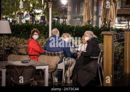 Foto di un vecchio caucasico bianco, clienti, di un bar ristorante sulla terrazza a belgrado, serbia, indossando una maschera respiratoria viso durante il co Foto Stock