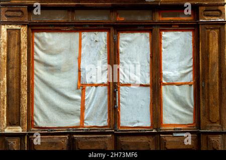 Facciata abbandonata dell'edificio con cornici in legno e finestre coperte in una strada tranquilla nel tardo pomeriggio Foto Stock