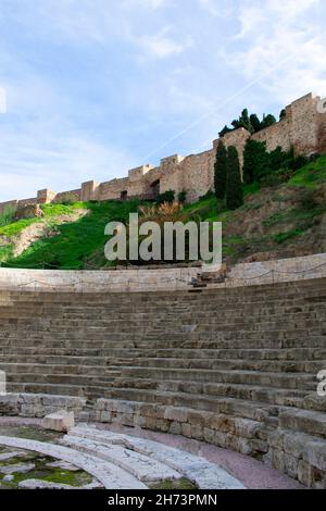 Bellissimo teatro storico romano, Malaga, Spagna. Verticale girato con l'antico monumento in primo piano, e il palazzo moresco Alcazaba nel bac Foto Stock