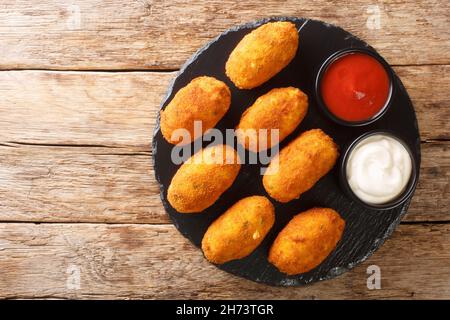 Crocchette spagnole con merluzzo salato servite con salse da vicino su un piatto di ardesia sul tavolo. Vista dall'alto orizzontale Foto Stock