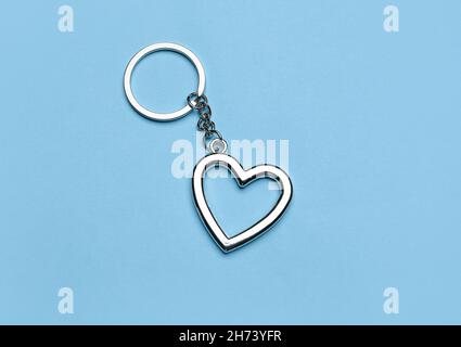 Portachiavi a forma di cuore in argento con portachiavi su sfondo blu Foto Stock