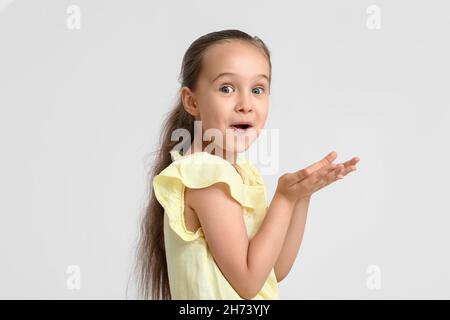 Sorprende la bambina in blusa gialla su sfondo bianco Foto Stock