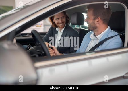 l'uomo riceve le chiavi di una nuova vettura da un responsabile delle vendite Foto Stock