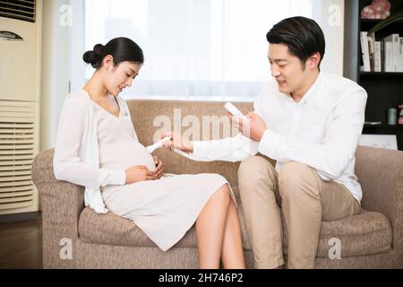 Giovane coppia con esami del cuore fetale a casa Foto Stock