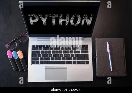 Vista dall'alto del notebook con testo python. Iscrizione Python sullo schermo del laptop e sulla tastiera. Impara il linguaggio di programmazione python, i corsi per computer, la formazione. Foto Stock