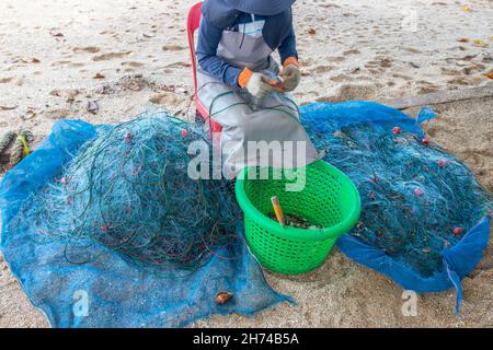 Riparazione e ispezione di una rete da pesca in spiaggia Foto Stock