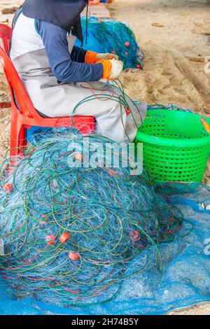 Riparazione e ispezione di una rete da pesca in spiaggia Foto Stock