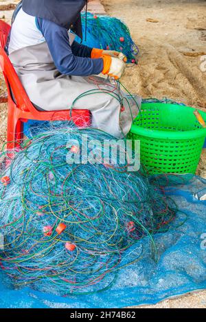 Riparazione e ispezione di una rete da pesca in spiaggia Foto Stock