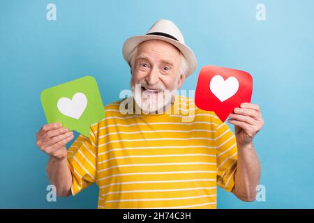 Ritratto di attraente anziano trendy uomo allegro tenendo in mano due carte come le carte isolate su sfondo di colore blu brillante Foto Stock