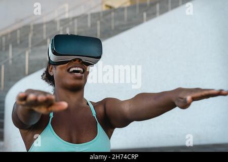 Happy FIT donna africana che utilizza cuffie per realtà virtuale durante la sessione di allenamento - tecnologia e concetto innovativo di allenamento Foto Stock