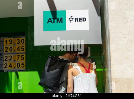 Una giovane coppia di turisti utilizza l'ATM per ritirare i contanti, mascherando il codice segreto con i loro corpi per prevenire il furto in Messico. Foto Stock
