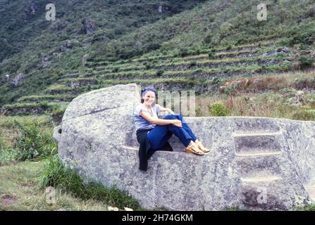 Giovane donna turistica si pone su una scala in pietra a Machu Picchu, Perù, Sud America 1975 Foto Stock