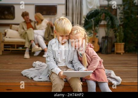 Bambini divertenti che usano il computer portatile al rimorchio, in campeggio Foto Stock