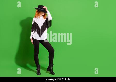 Vista completa del corpo della ragazza attraente che tocca il cappello posa indossare costume guardare isolato su sfondo di colore verde chiaro Foto Stock