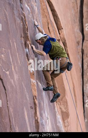 Un arrampicatore si alza sul percorso nervoso di Suburbia nell'area di arrampicata di Wall Street da Moab, Utah. Foto Stock