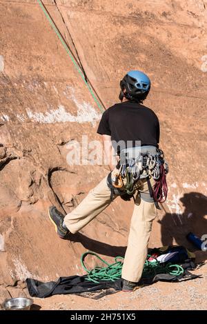 Un arrampicatore sfreccia un altro arrampicatore sulla via di arrampicata sopra di lui vicino a Moab, Utah. Foto Stock