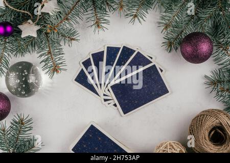 Le carte Tarot si rifanneriscono su una superficie di cemento bianco con rami e decorazioni dell'albero di Natale. Minsk, Bielorussia, 19.11.2021 Foto Stock