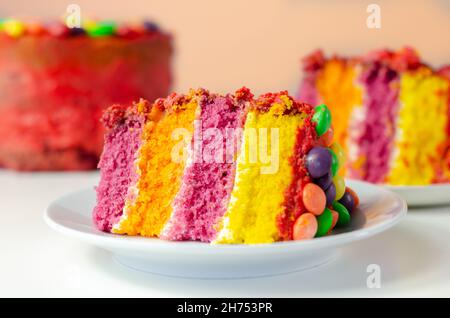 Torta per la celebrazione dell'arcobaleno, pan di Spagna colorato riempito  e ricoperto di glassa e decorato a mano con caramelle di frutta masticante  in una croccante guscio di zucchero Foto stock 