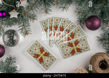 Le carte Tarot si rifanneriscono su una superficie di cemento bianco con rami e decorazioni dell'albero di Natale. Minsk, Bielorussia, 19.11.2021 Foto Stock