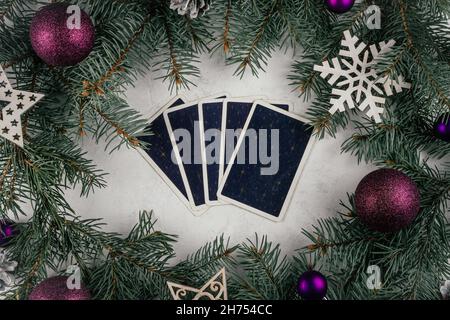 Le carte Tarot si rifanneriscono su una superficie di cemento bianco con rami e decorazioni dell'albero di Natale. Minsk, Bielorussia, 19.11.2021 Foto Stock