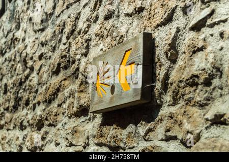 Primo piano di Scallop simbolo della strada di Santiago con una freccia su un muro di pietra in Cantabria, Spagna. Foto Stock