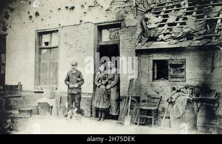 Una visione storica della famiglia francese che si trova fuori dalla loro casa danneggiata in Becourt Street ad Albert, Somme, Francia, durante la prima guerra mondiale. Foto Stock
